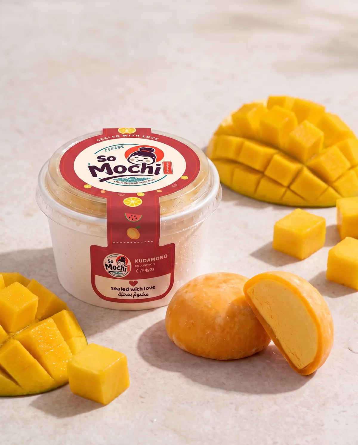 Jumbo Mango mochi, whole and cut open, beside its sealed So Mochi cup
