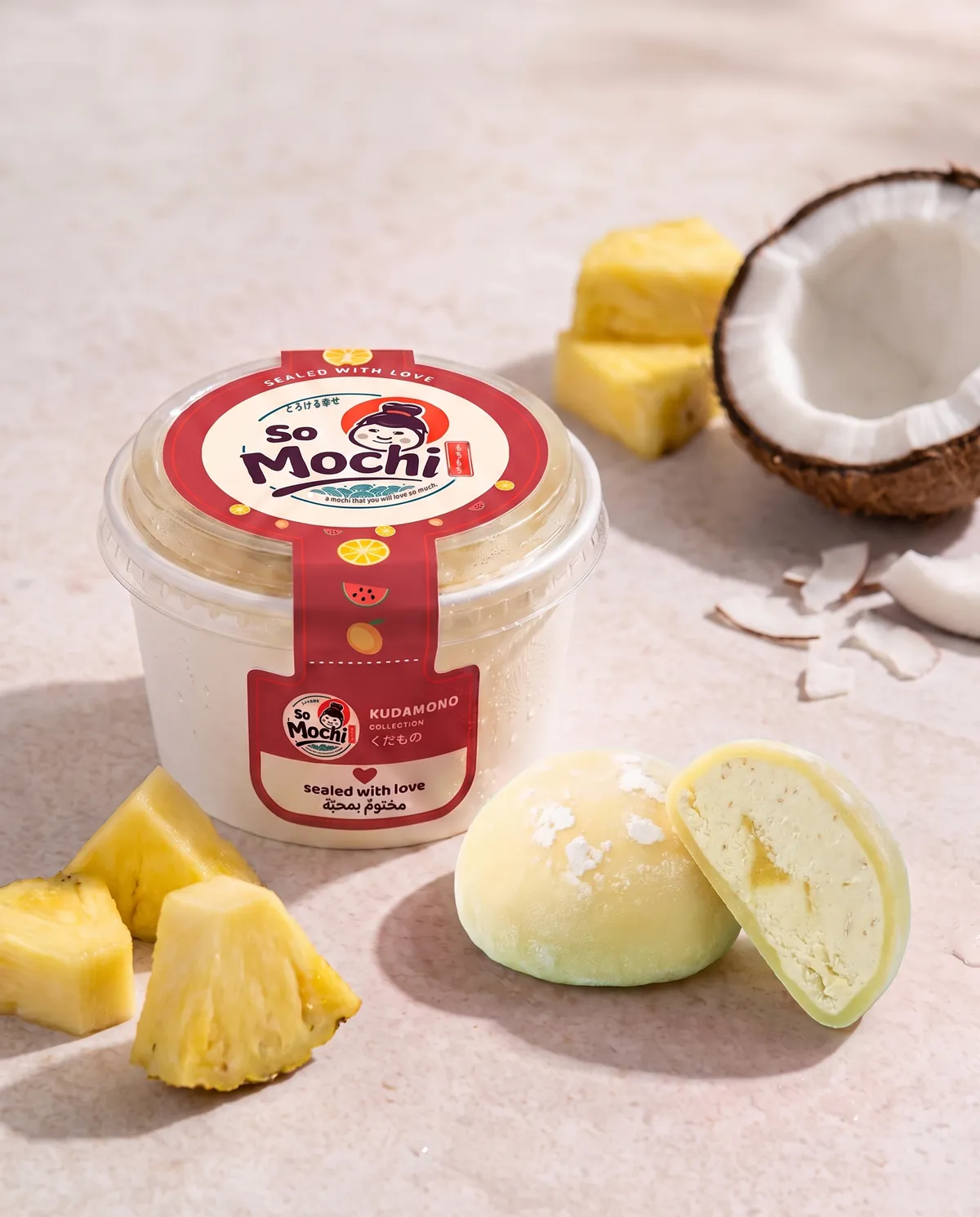 Jumbo Piña Colada mochi, whole and cut open, beside its sealed So Mochi cup