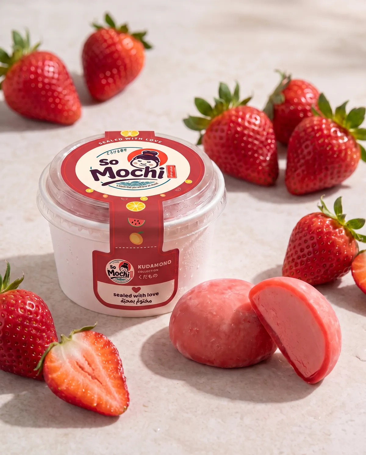 Jumbo Strawberry mochi, whole and cut open, beside its sealed So Mochi cup