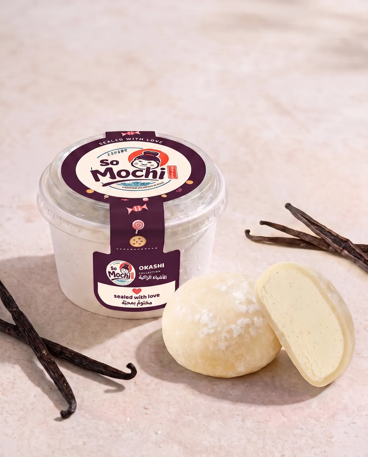 Jumbo Vanilla mochi, whole and cut open, beside its sealed So Mochi cup