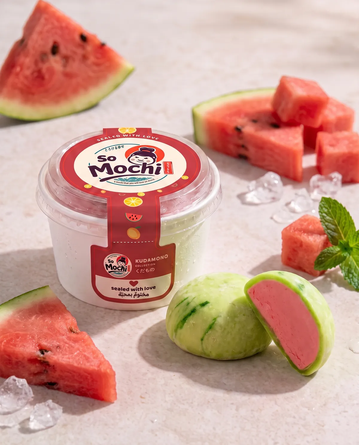 Jumbo Watermelon mochi, whole and cut open, beside its sealed So Mochi cup